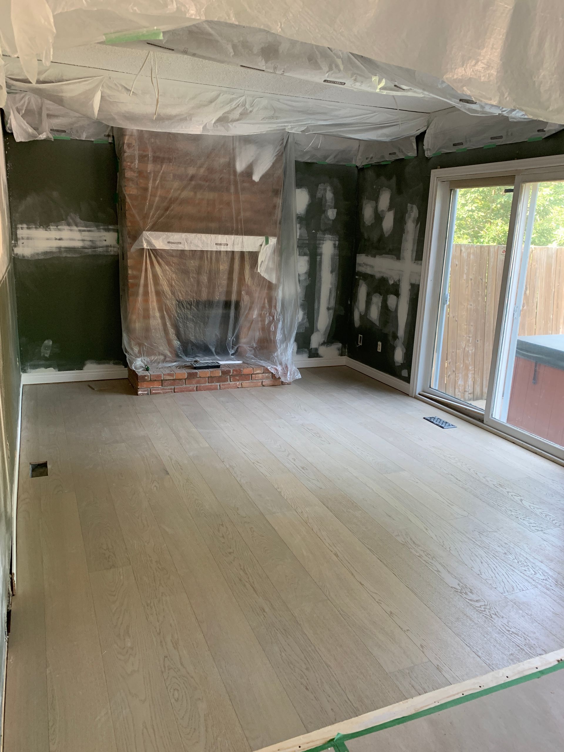 A living room with a fireplace and sliding glass doors is being remodeled.