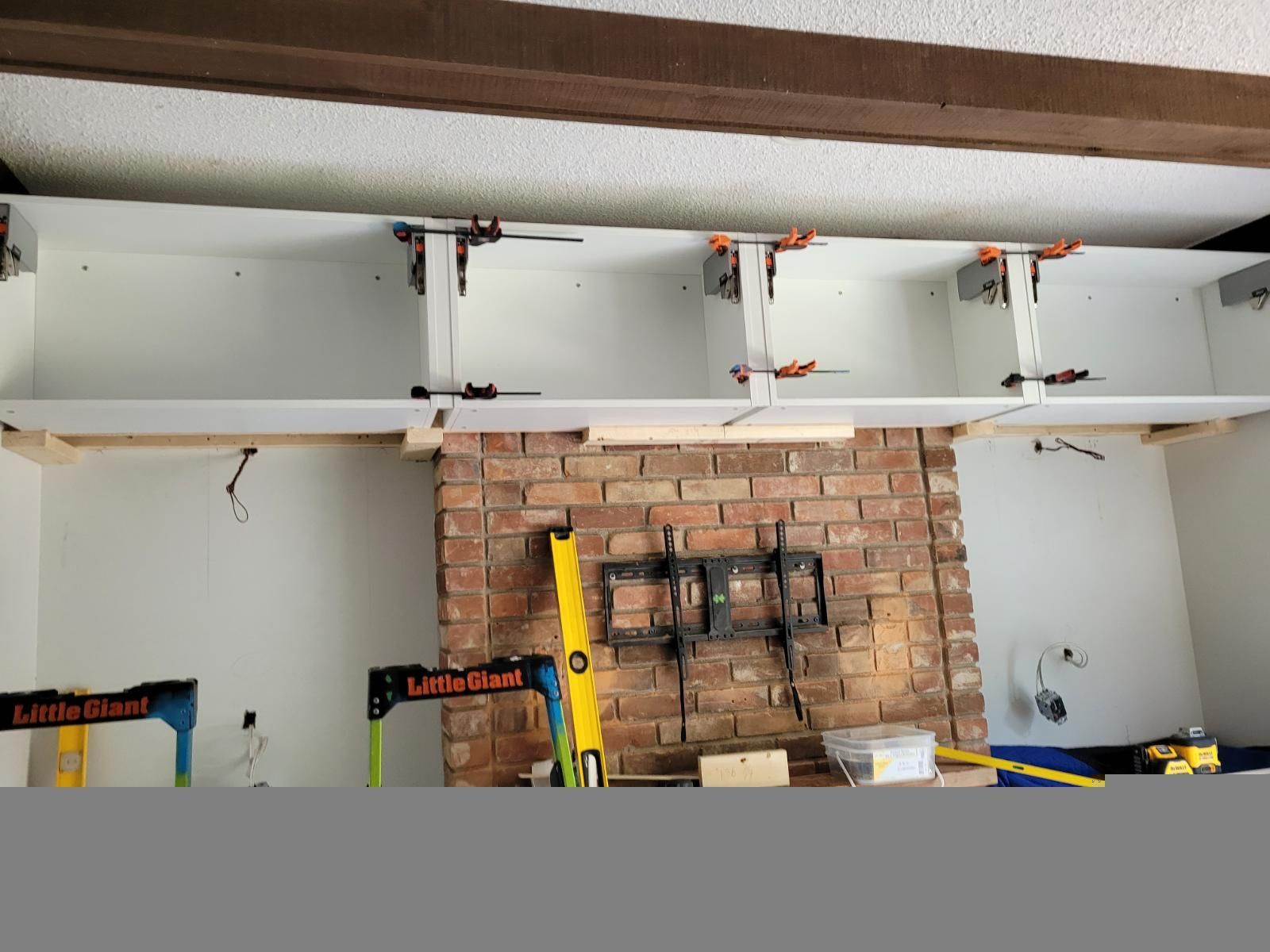 Partially renovated room with exposed brick wall, ceiling beams, and construction tools on a workbench