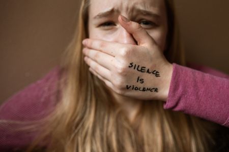 A person covering their mouth with their hand, which has the words 