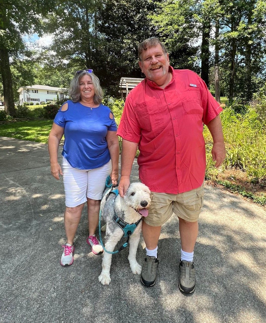 A man and woman are standing next to a dog on a leash.
