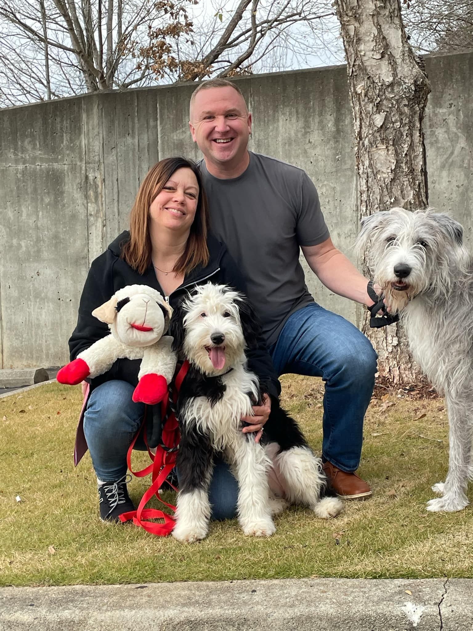 A man and a woman are posing for a picture with their dogs.