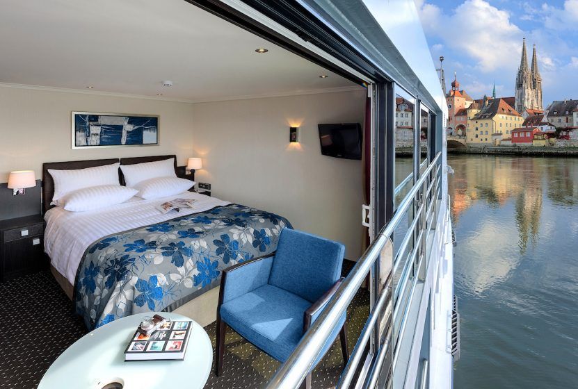 A hotel room with a large bed and a balcony overlooking the water.