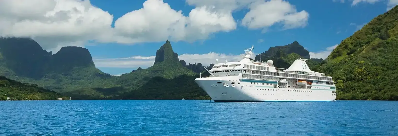 A large cruise ship is floating on top of a body of water surrounded by mountains.