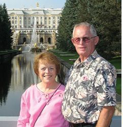 A man and a woman are posing for a picture in front of a fountain.