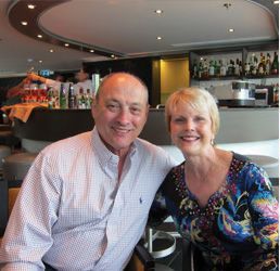 A man and a woman are posing for a picture in a restaurant.