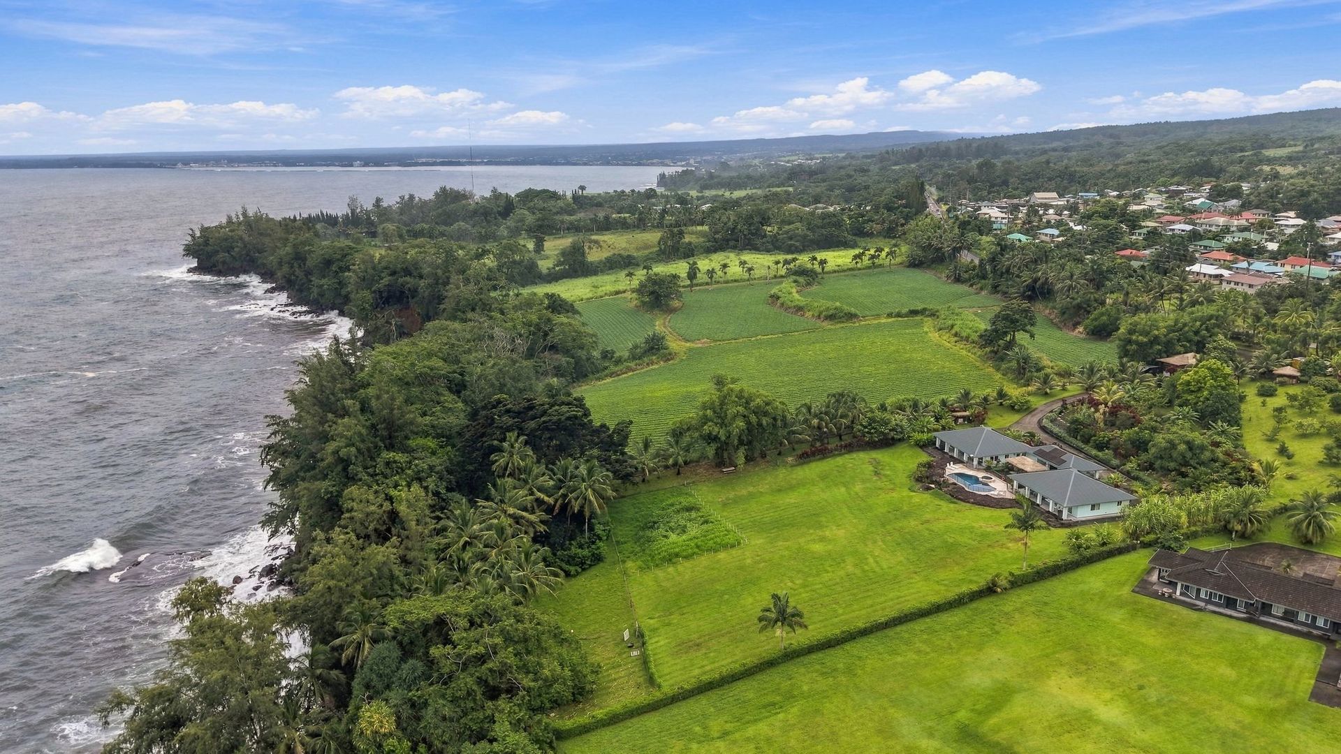Koili Point’s two homes above the rocky Papaikou coastline, with Hilo Bay in the distance.