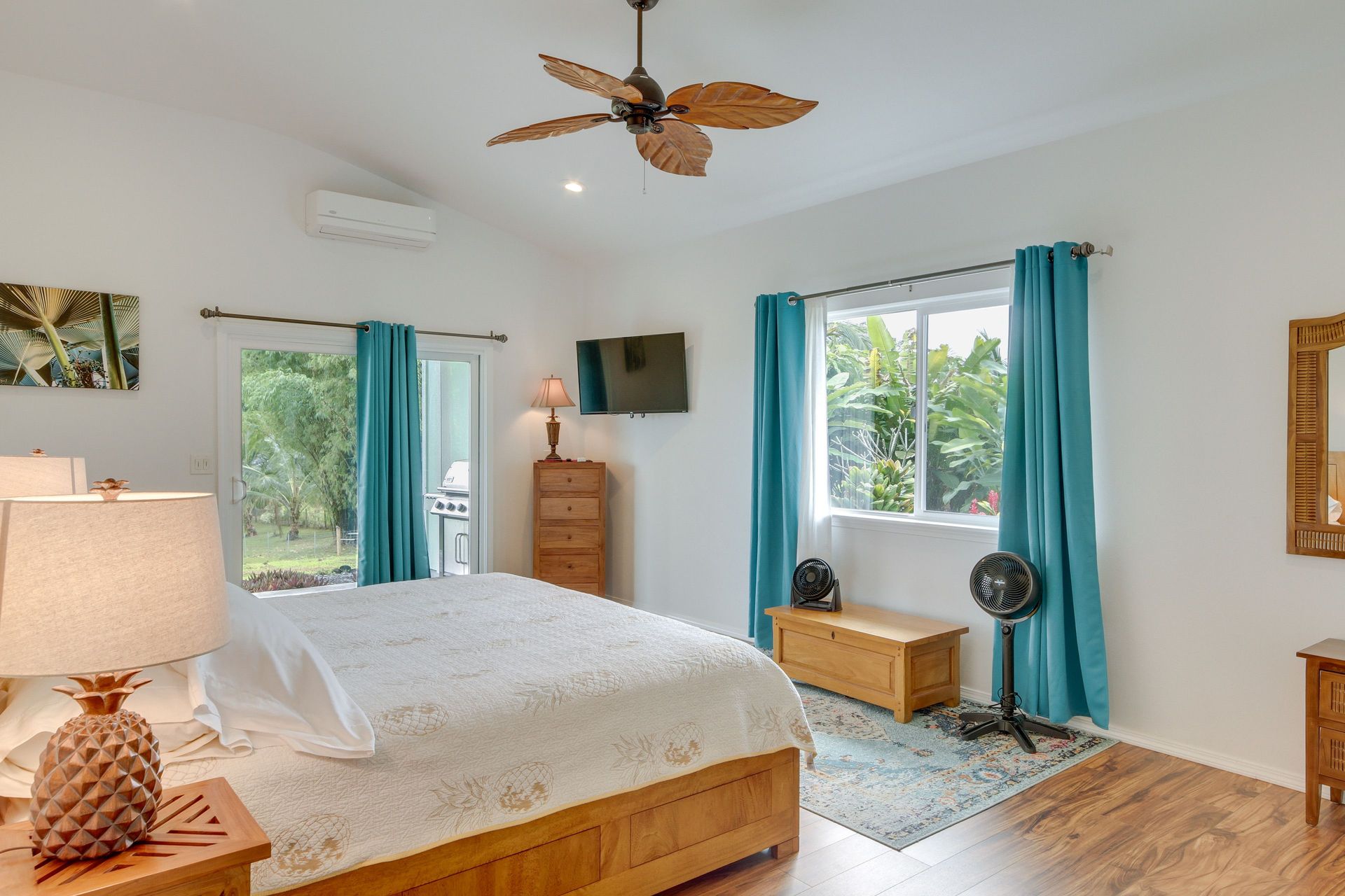 Hale Honu: Bedroom with wood furniture, white walls, teal curtains, bed, TV, and ceiling fan.