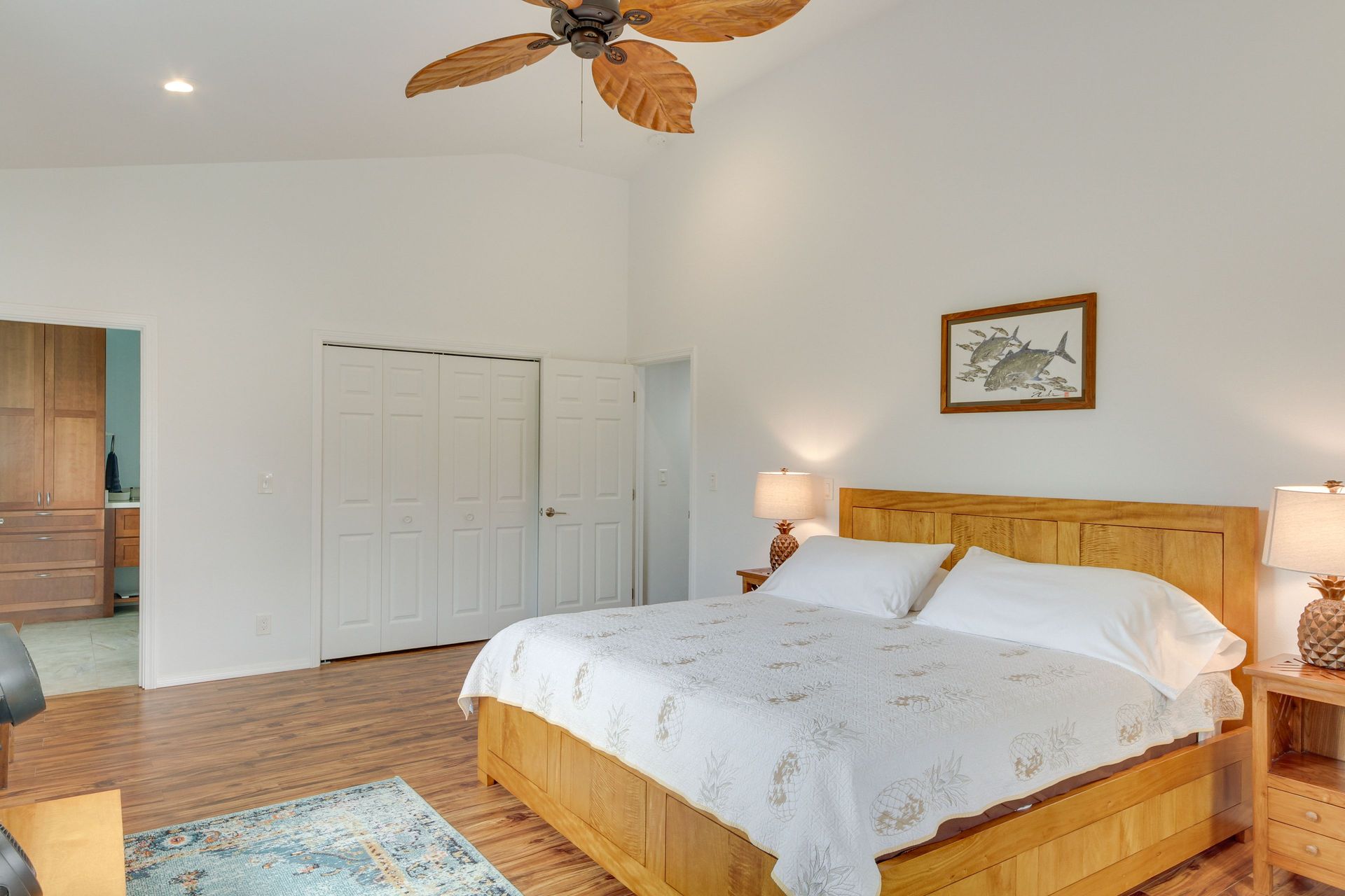 Hale Honu: Bedroom with a wooden bed, closet, and ceiling fan. Light wood floors and walls.