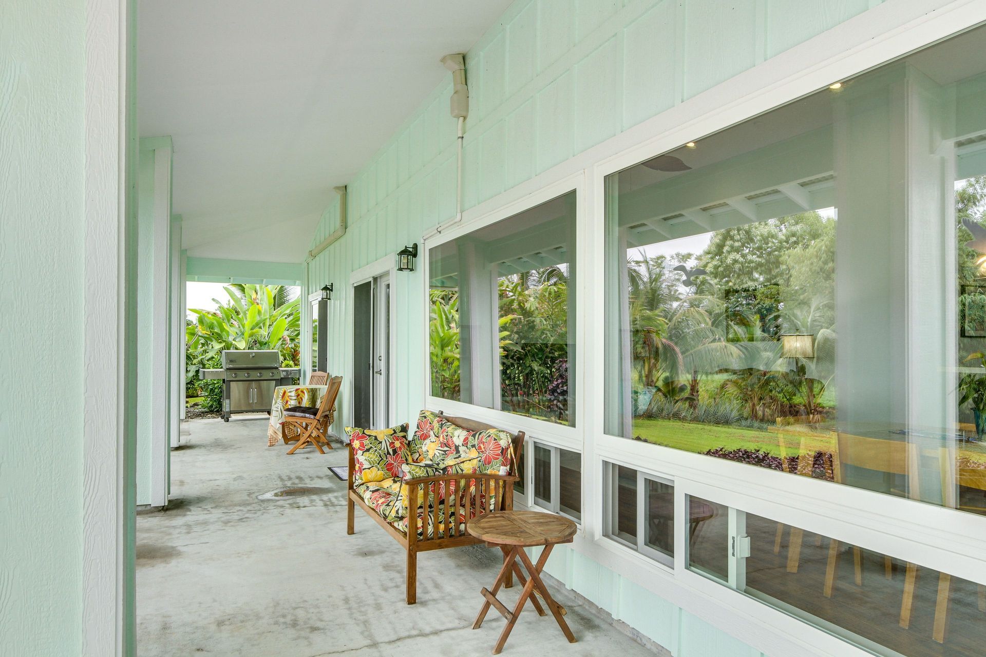 Hale Honu: Covered outdoor patio with a seating area and large windows overlooking a yard.