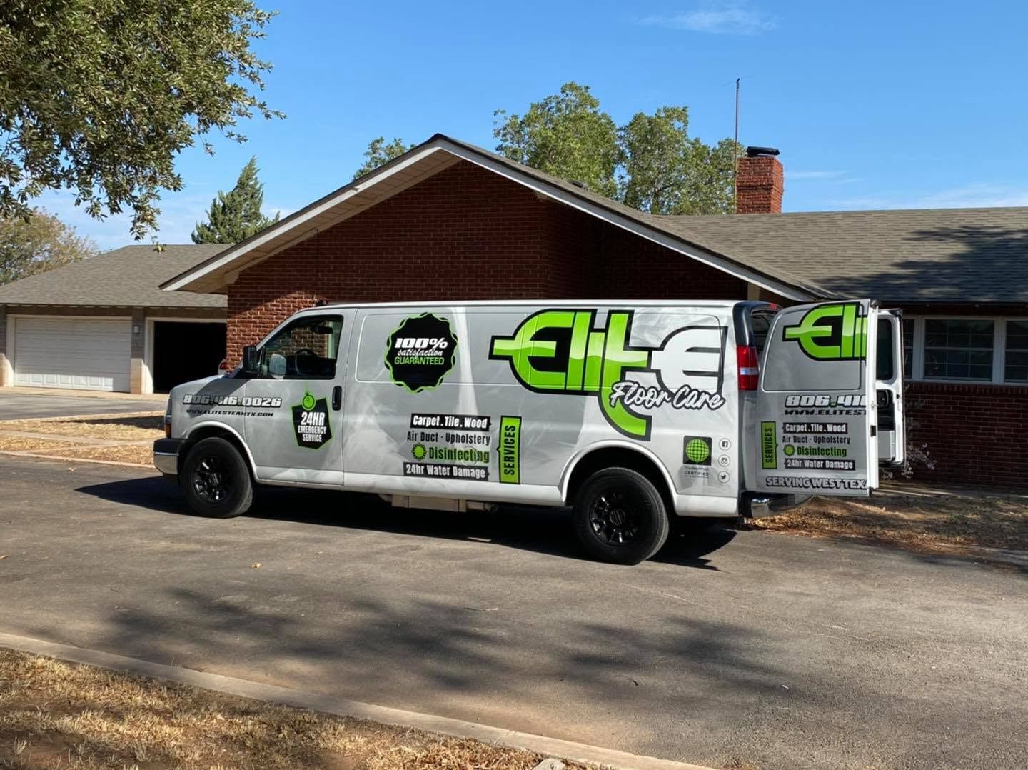 White service van with green logo parked in a suburban driveway on a sunny day