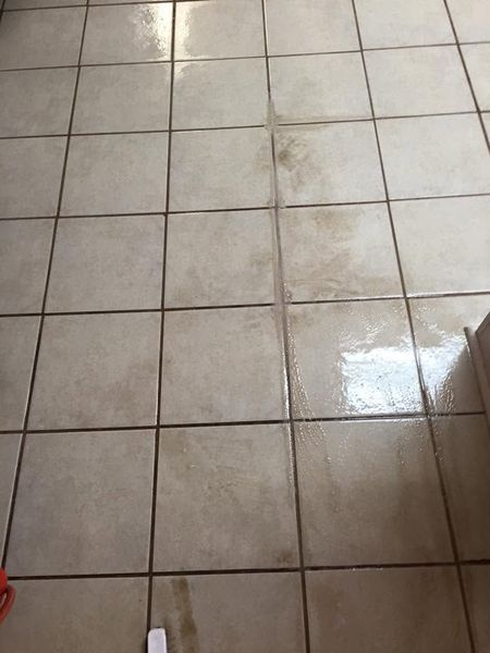 Wet beige tiled floor with a shiny reflection and grout lines.