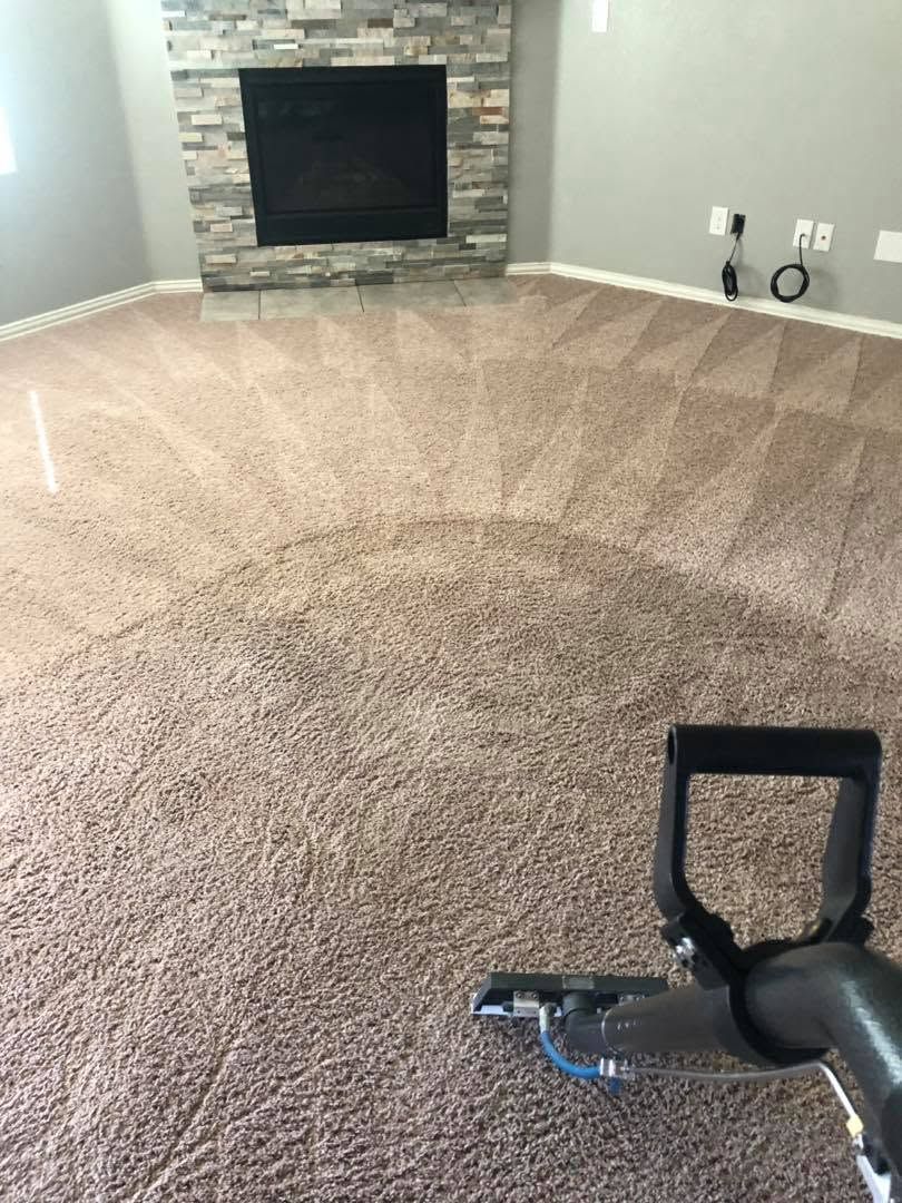 Carpeted living room with stone fireplace; vacuum cleaner handle in foreground.