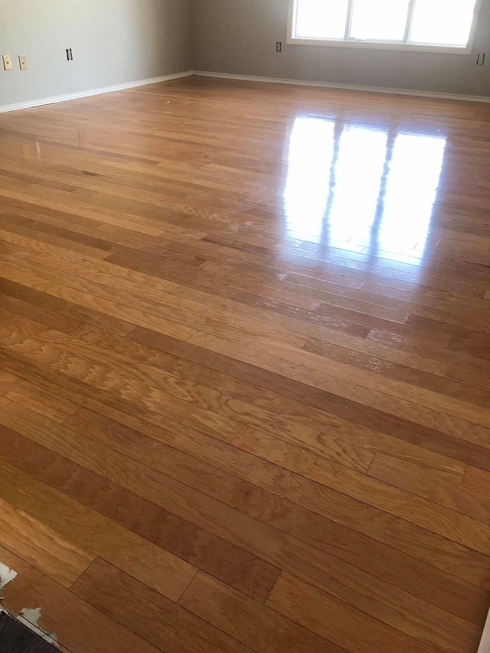 Empty hardwood-floored room with sunlight reflecting from a window.