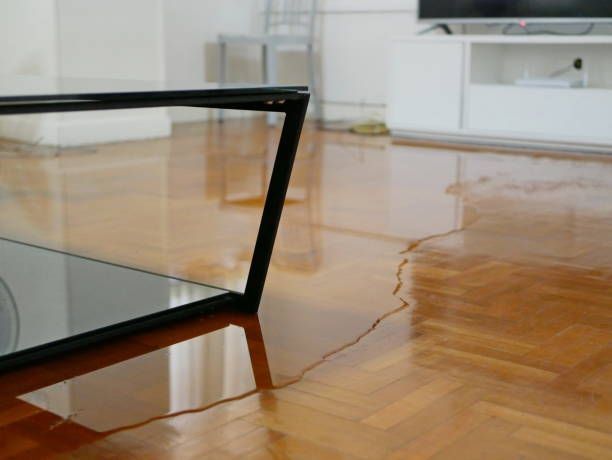 Broken glass coffee table on a wooden floor, with a cracked tabletop in a bright room