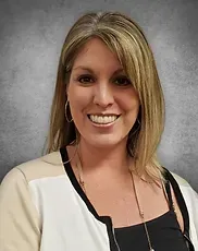 A woman wearing a white jacket and a black shirt is smiling for the camera.