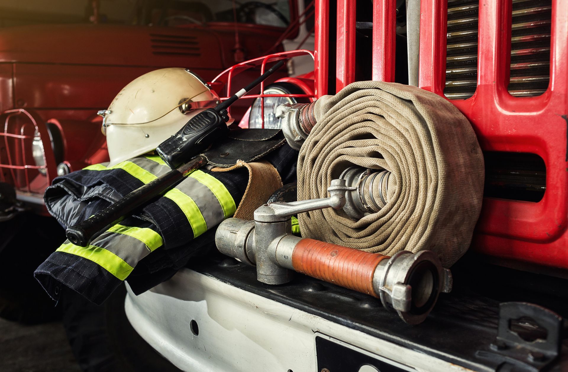A fire truck with a helmet , gloves , and hose on the bumper.