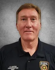 A man is wearing a black polo shirt and a badge on his chest.