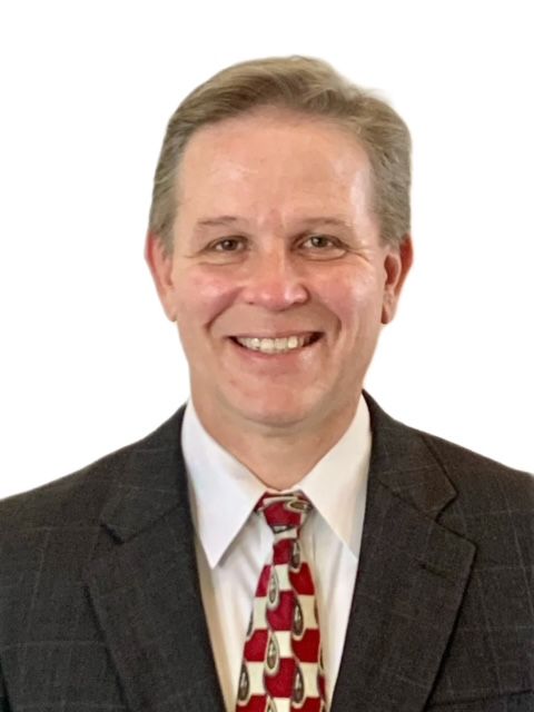 A man in a suit and tie is smiling for the camera