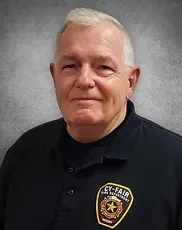 A man is wearing a black shirt with a badge on it.