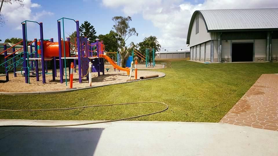 A Playground With A Large Building In The Background — Marian Lawns In Marian, QLD