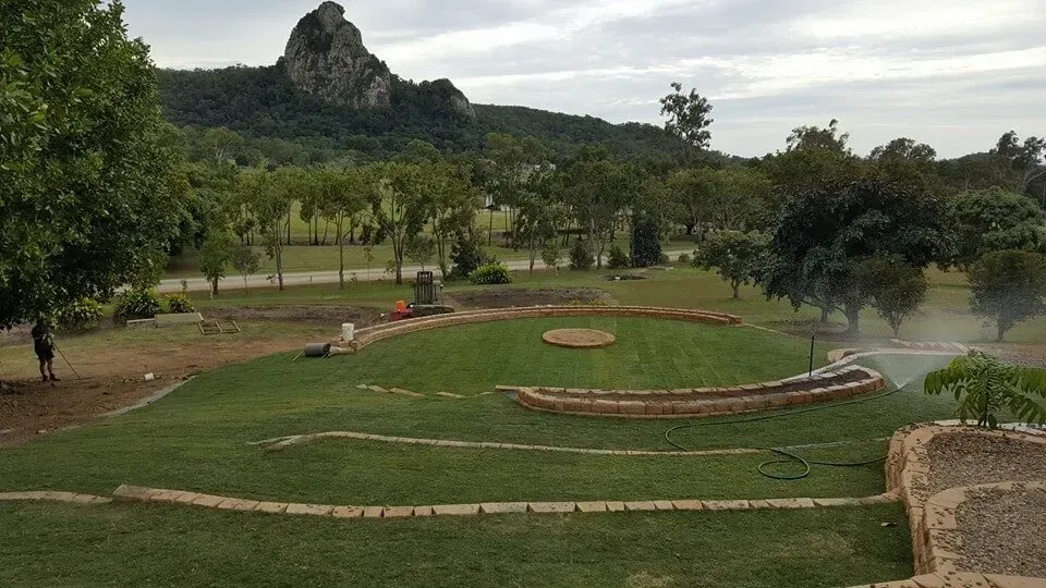 A Large Lush Green Field With A Mountain In The Background — Marian Lawns In Marian, QLD