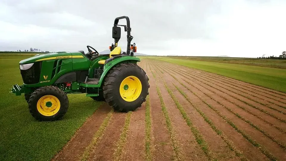 A John Deere Tractor Is Driving Through A Field Of Grass — Marian Lawns In Marian, QLD