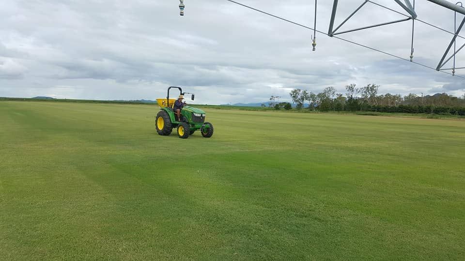 A Green Tractor Is Driving Through A Lush Green Field — Marian Lawns In Marian, QLD