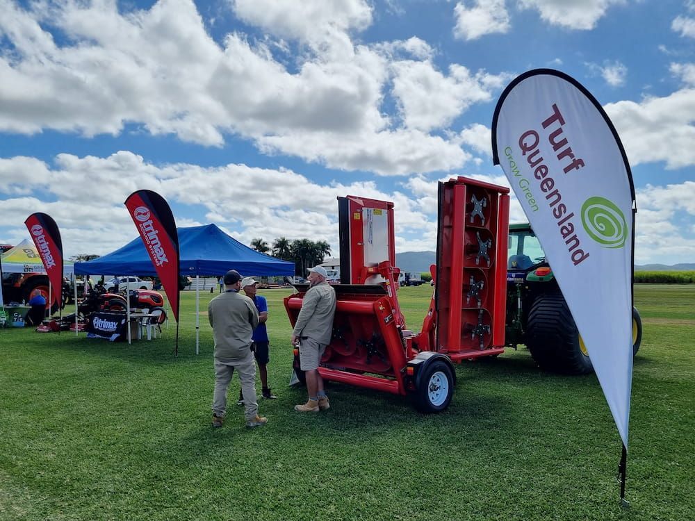 A Group Of People Are Standing Around A Tractor In A Field — Marian Lawns In Marian, QLD