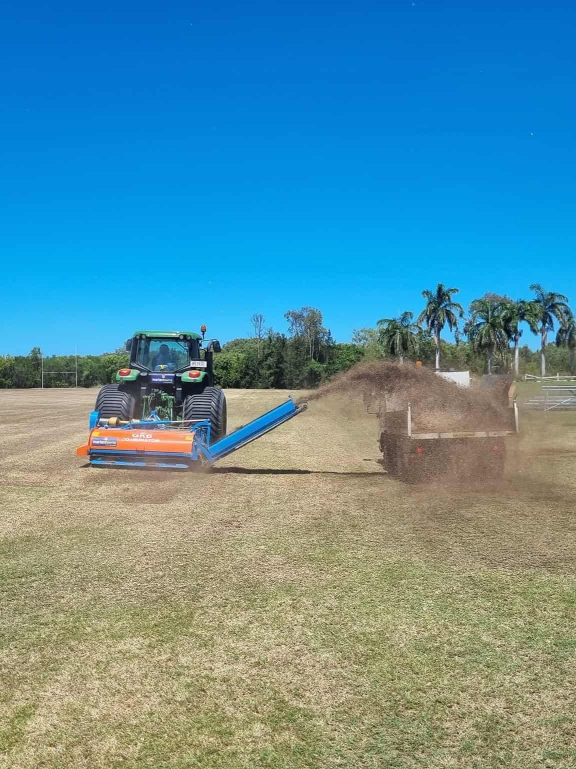 A Tractor Is Spreading Fertilizer On A Lush Green Field — Marian Lawns In Bowen, QLD