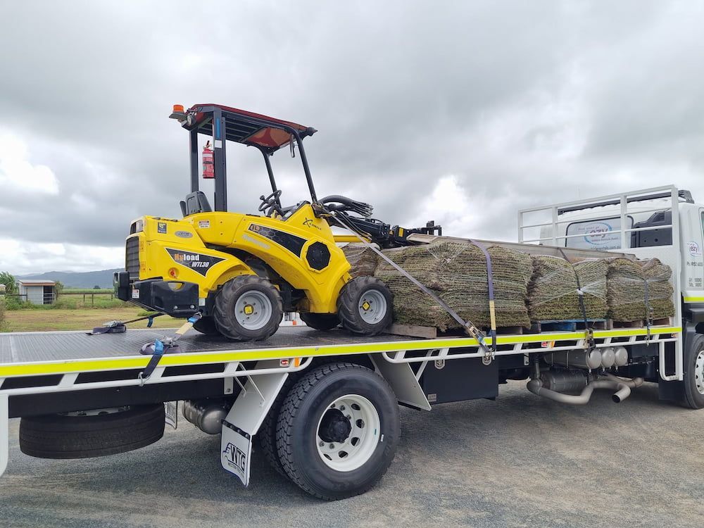 A Yellow Forklift Is Sitting On Top Of A Flatbed Truck — Marian Lawns In Marian, QLD