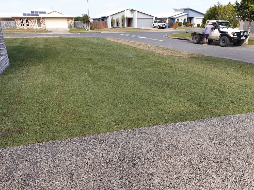 A White Truck Is Parked On The Side Of The Road Next To A Lush Green Lawn — Marian Lawns In Marian, QLD