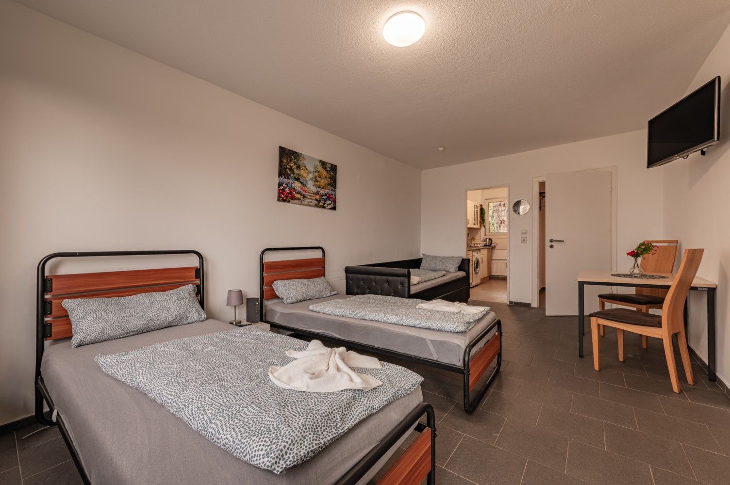 Gemeinsames Schlafzimmer mit drei Einzelbetten, einem kleinen Schreibtisch und Stuhl 