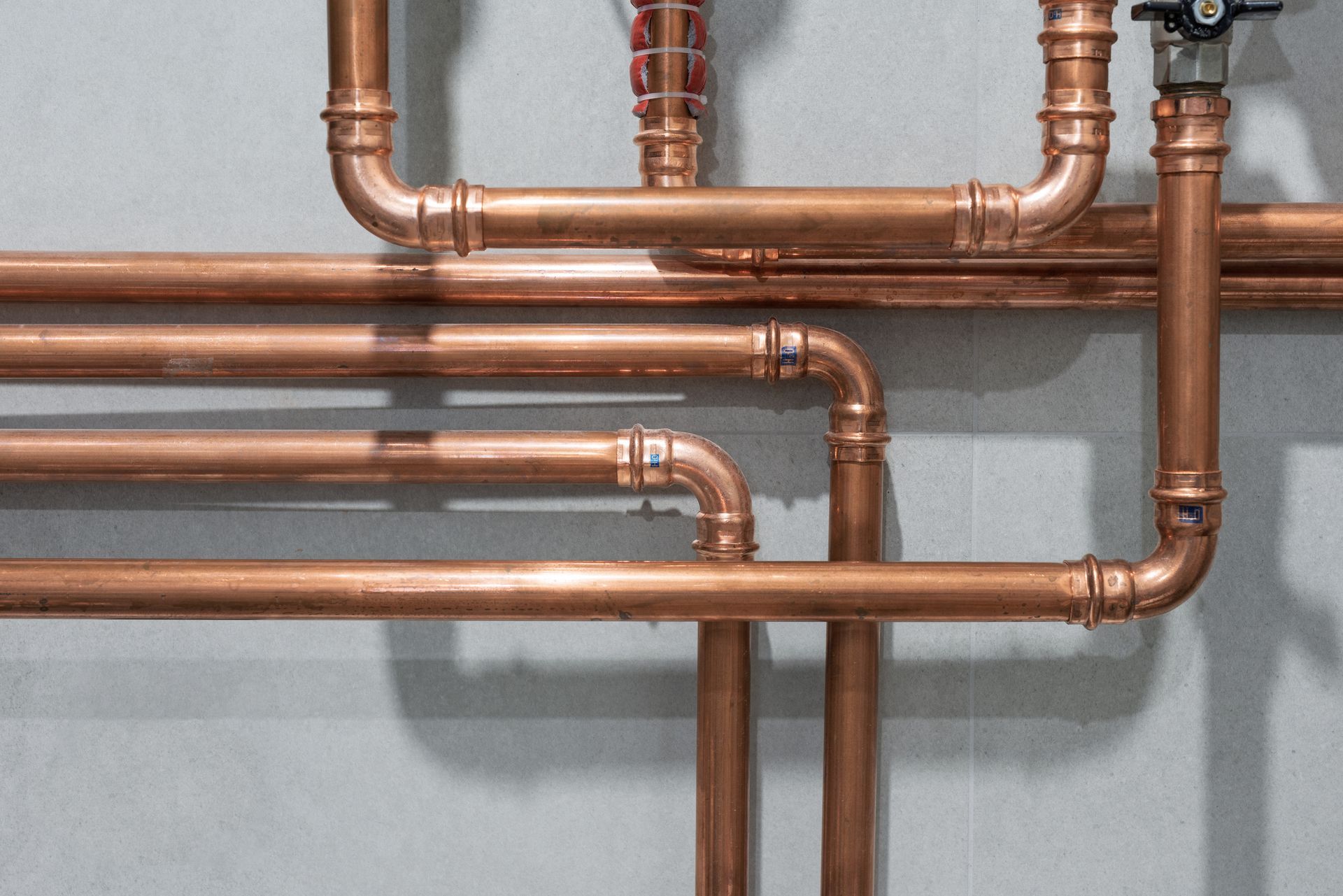 Copper pipes and fittings on a gray wall.
