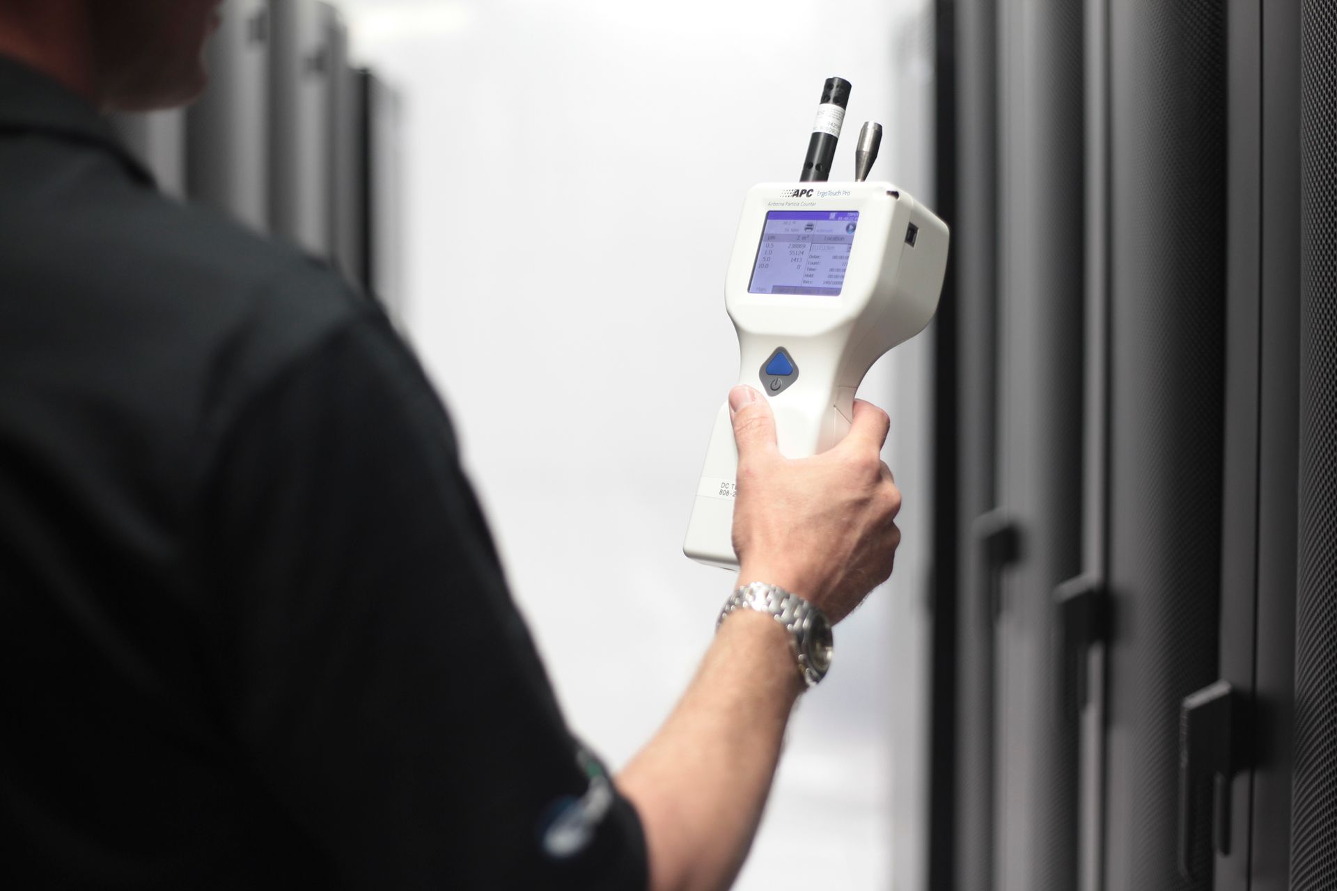 A man in a black shirt is holding a white device in his hand.