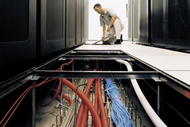 A man is vacuuming the floor of a server room