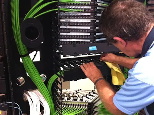 A man is working on a server with green wires