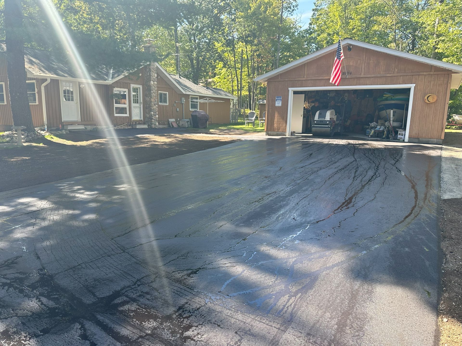 Blacktop driveway leading to a garage with an American flag, in a residential neighborhood.