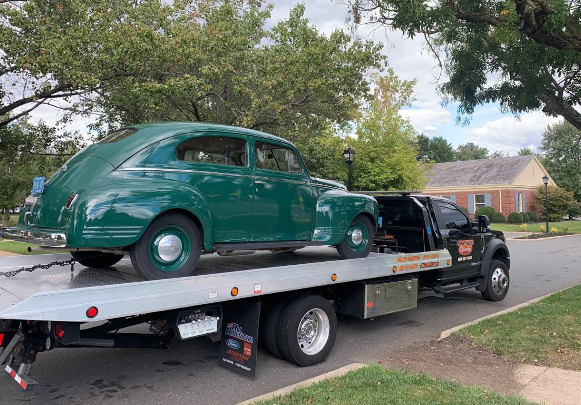 Green vintage car on a tow truck.