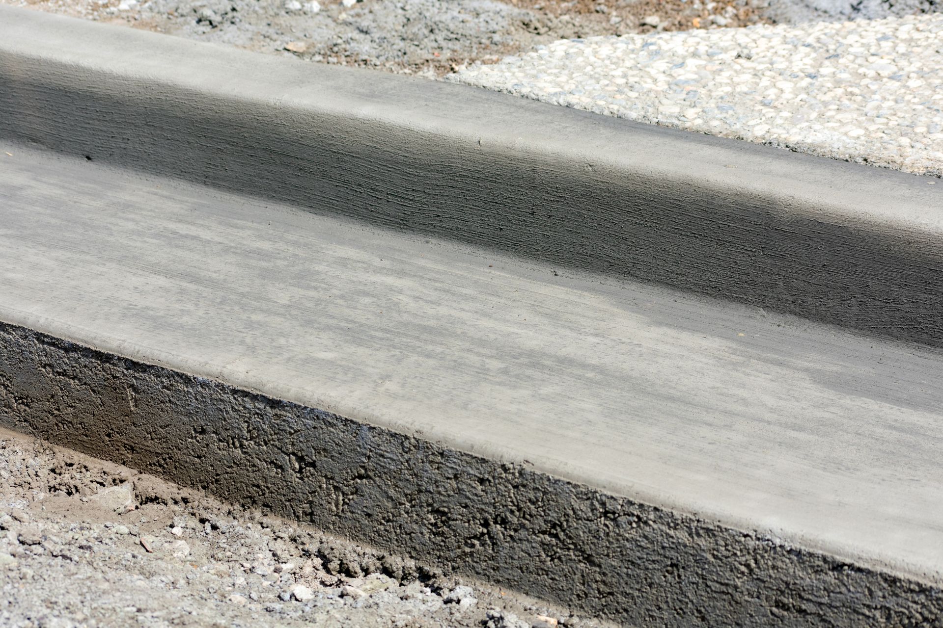 a close up of a concrete curb with gravel in the background