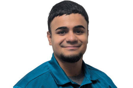 A person with short dark hair and a small goatee wearing a teal collared shirt, smiling against a white background.