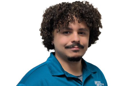 A person with curly hair and a mustache wearing a teal polo shirt against a white background.