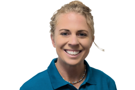A person with blonde hair in a ponytail smiles, wearing a blue polo shirt and a beaded necklace against a white background.