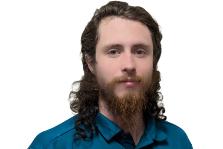 A person with long wavy brown hair and a beard, wearing a teal collared shirt against a plain white background.