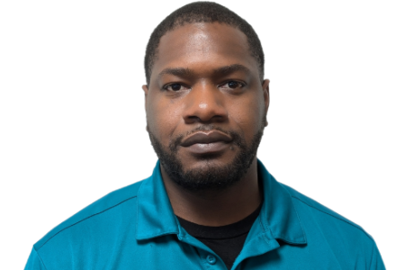 A man with a beard, wearing a teal collared shirt over a black crew-neck shirt, looking directly at the camera.