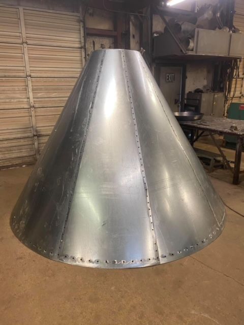 a large metal cone is sitting on the floor in a room .
