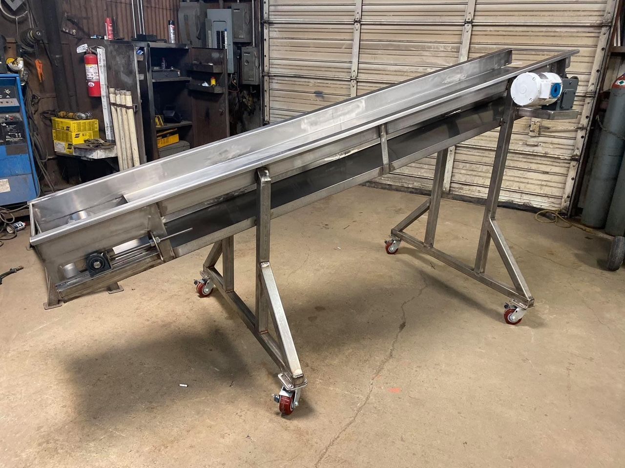 a stainless steel conveyor belt is sitting on a stand in a room .