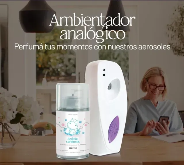 Ambientador analógico con aerosol blanco sobre una mesa; al fondo, una mujer usa el móvil en una sala