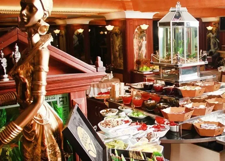 A buffet spread featuring various dishes in bowls, illuminated by a tall metal lantern in a warmly lit, elegant setting.