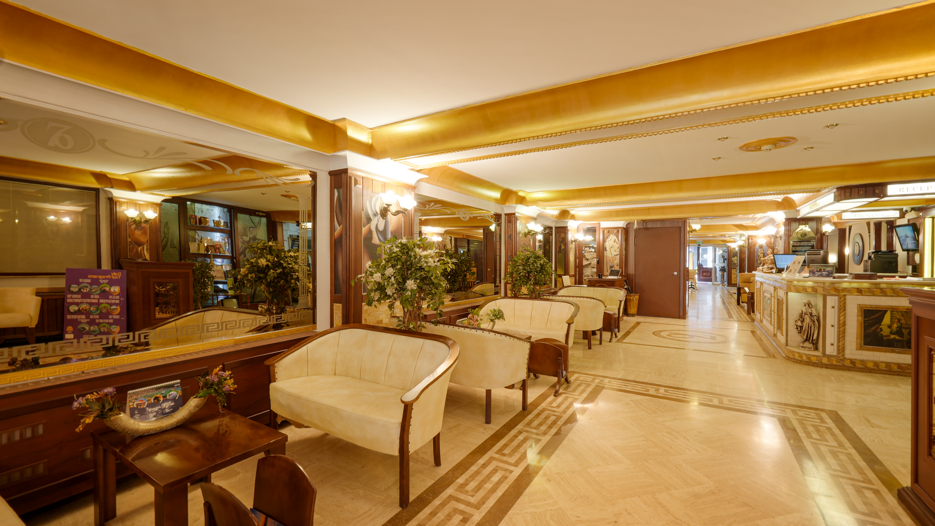 İzmir Park Hotel lobby featuring light cream sofas, warm gold accents, and patterned tile floors leading to a reception.