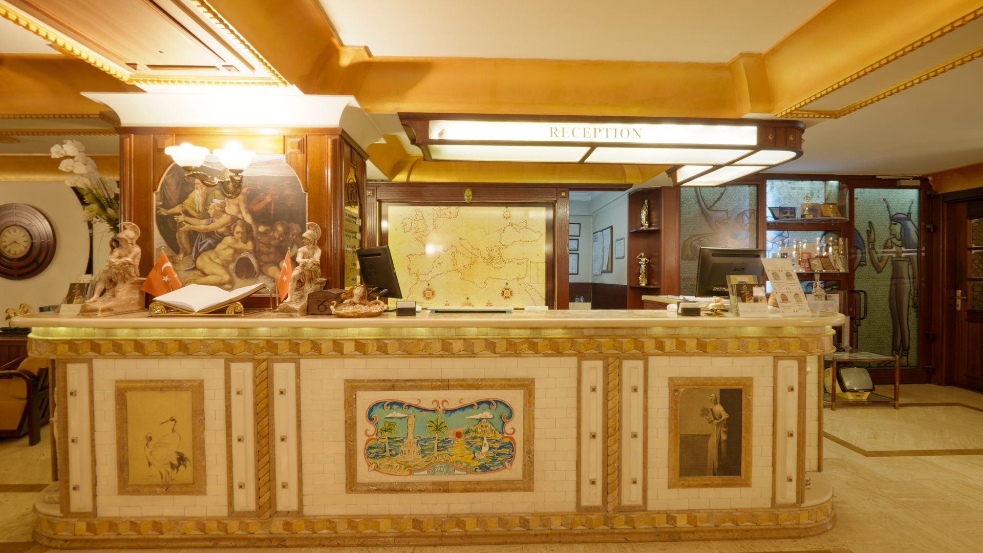A hotel reception desk with a cream and gold marble counter, decorative tiled panels, and warm ambient lighting.